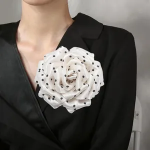 Close-up of French style polka dot fabric peony flower brooch on a black blazer