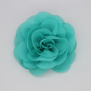 Vista detallada de un broche de flor de tela rosa 3D de gasa color turquesa