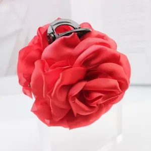 Close-up of elegant red satin rose flower hair claw clip with delicate fabric petals