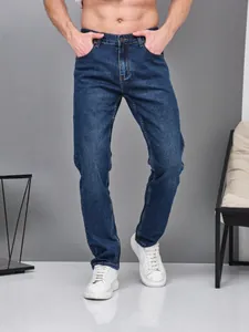 Close-up of men's slim straight dark blue stretch denim jeans with white sneakers