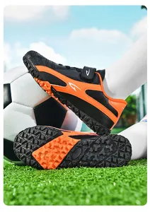 Vue détaillée de chaussures de football enfant noires et oranges avec semelles turf