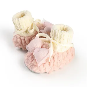 Close-up of pink fuzzy baby booties with knit cuffs and decorative bow detail