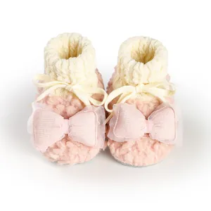 Detailed macro view of soft pink plush baby booties with elegant bows for infant girls