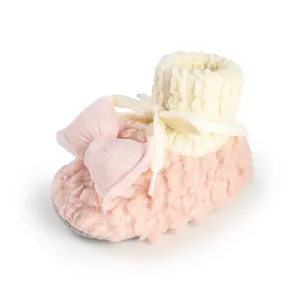 Detailed view of pink plush baby winter shoes with cute bow and knitted cuff