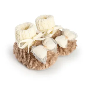 Close-up view of warm plush winter baby booties featuring soft fur and mesh bow detail