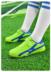 Détail de chaussures de football pour enfants vert fluo sur gazon synthétique