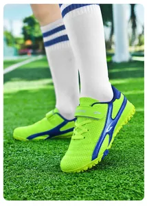 Crampons de football vert néon pour enfants sur un terrain de gazon synthétique