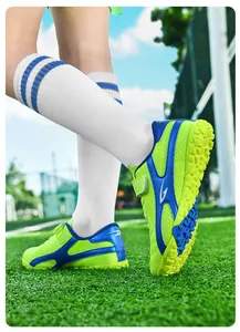 Vue détaillée de chaussures de football enfant vert fluo avec accents bleus sur gazon
