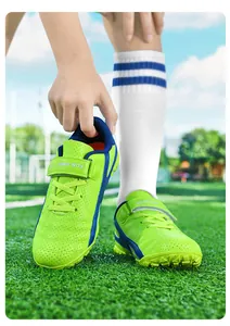 Gros plan de chaussures de football vertes pour enfants avec velcro sur le terrain.