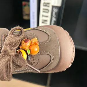Detailed view of brown children's sneakers with cute bear ornament and anti-kick toe.