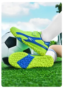 Gros plan de chaussures de football enfant vertes montrant les crampons durables