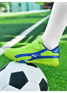 Détail de chaussure de football pour enfants vert citron et bleu sur un ballon de foot