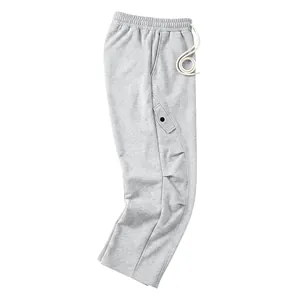 Détail rapproché du pantalon de jogging gris ample avec un design de couture incurvée.