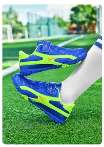 Vue latérale de chaussures de football pour enfants bleu et vert fluo sur un terrain