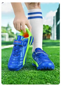 Vue détaillée de chaussures de football pour enfants bleu et jaune sur terrain vert