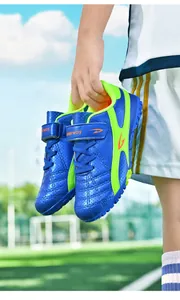 Vue détaillée de chaussures de football pour enfants bleu et vert avec scratch sur gazon