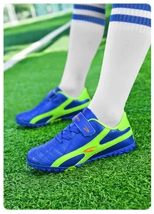 Gros plan de chaussures de football pour enfants bleues et vertes sur gazon