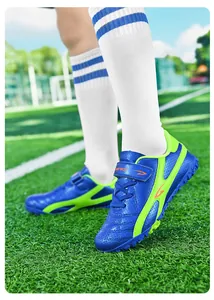 Chaussures de football bleues et vertes pour enfants sur terrain de sport vue détaillée