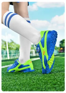 Gros plan de chaussures de football pour enfants bleu et citron sur terrain synthétique