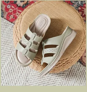 Women's sage green wedge sandals with laser-cut straps on a woven surface