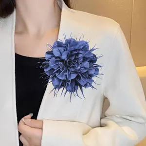 Detailopname van een luxe 18 cm grote blauwe stoffen bloembroche op een witte blazer