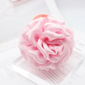 Close-up view of a large pink satin rose hair claw clip with elegant petal details