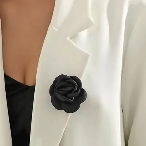 Detailansicht einer 6cm handgefertigten schwarzen Kamelienblüte auf weißem Blazer