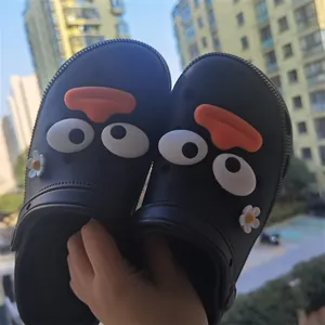 Close-up of funny cartoon big eyes and mouth charms on black garden clogs accessories