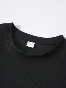 Close-up detail of the textured neckline and care label on a solid black sweatshirt