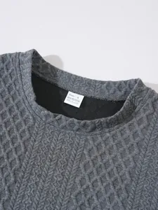 Detailed close-up of grey textured knit sweater showing neckline and fabric composition tag
