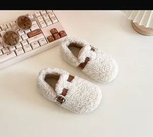 Detail of cream faux shearling baby walking shoes with decorative brown buckle strap