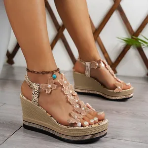 Detailed view of women's wedge sandals with decorative butterflies and rhinestone platform.
