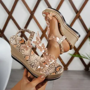 Close-up view of intricate butterfly rhinestone accents on snake print platform wedge sandals