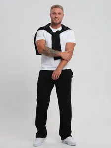 Detailed view of a Caucasian model wearing loose straight black cotton sweatpants in studio