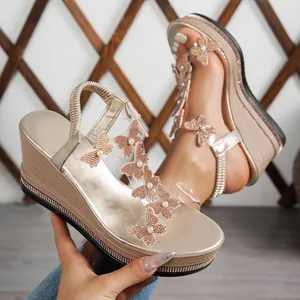 Detailed view of champagne wedge sandals with rhinestone butterfly and platform sole.