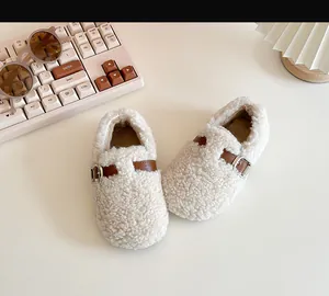 Close-up detail of cozy cream fleece toddler walking shoes featuring a brown buckle strap
