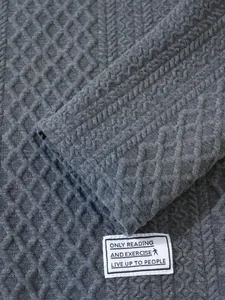 Macro detail of dark grey waffle texture knit sweater featuring a white decorative tag.