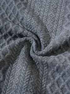 Macro detail shot of grey textured knit sweater fabric showing intricate diamond patterns