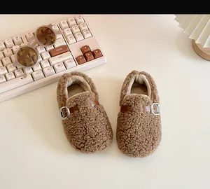 Close-up of cozy brown sheep wool baby shoes with elegant metal buckle detail.
