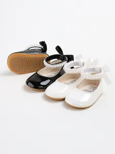 Detail view of black and white baby princess shoes with pearl straps and soft soles.