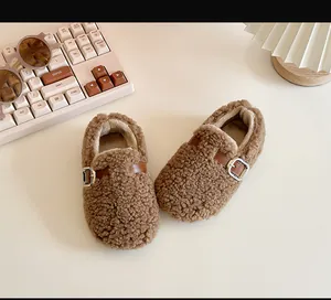 Close-up of cozy brown sheepskin fleece toddler shoes with a stylish metal buckle detail