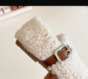 Close-up detail of plush lamb wool toddler shoe with decorative brown buckle strap