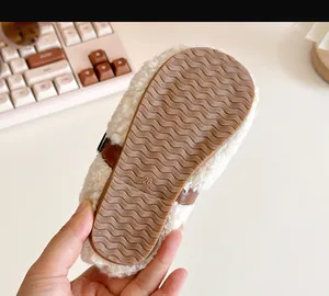 Detailed view of the brown non-slip wavy rubber sole on a white baby sherpa shoe