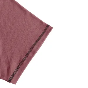 Macro detail showing black contrast stitching on a dusty rose t-shirt sleeve edge.