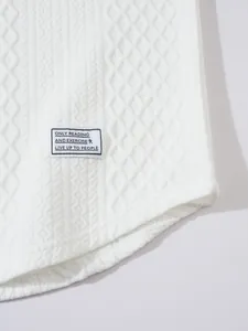 Close-up view of a white textured sweater featuring a motivational fabric patch