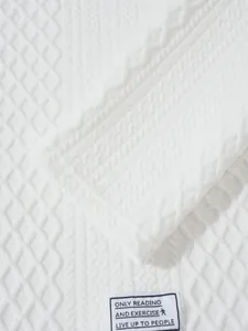 Detailed macro view of white knitted fabric texture with embossed patterns and label