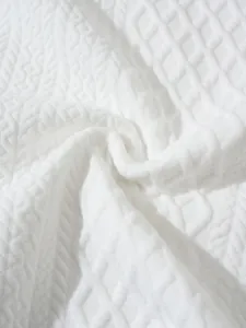 Macro close-up of white textured knit sweater fabric with geometric embossed pattern