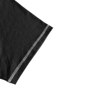 Detailed macro shot of black t-shirt fabric with white contrast stitching on the sleeve.