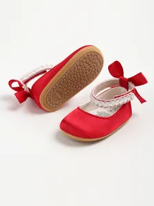 Close-up view of red satin baby princess shoes featuring pearls and non-slip soft sole