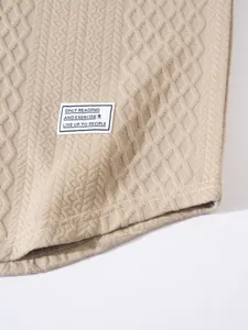 Close-up detail of beige textured knit fabric and sewn-on brand label on a sweatshirt